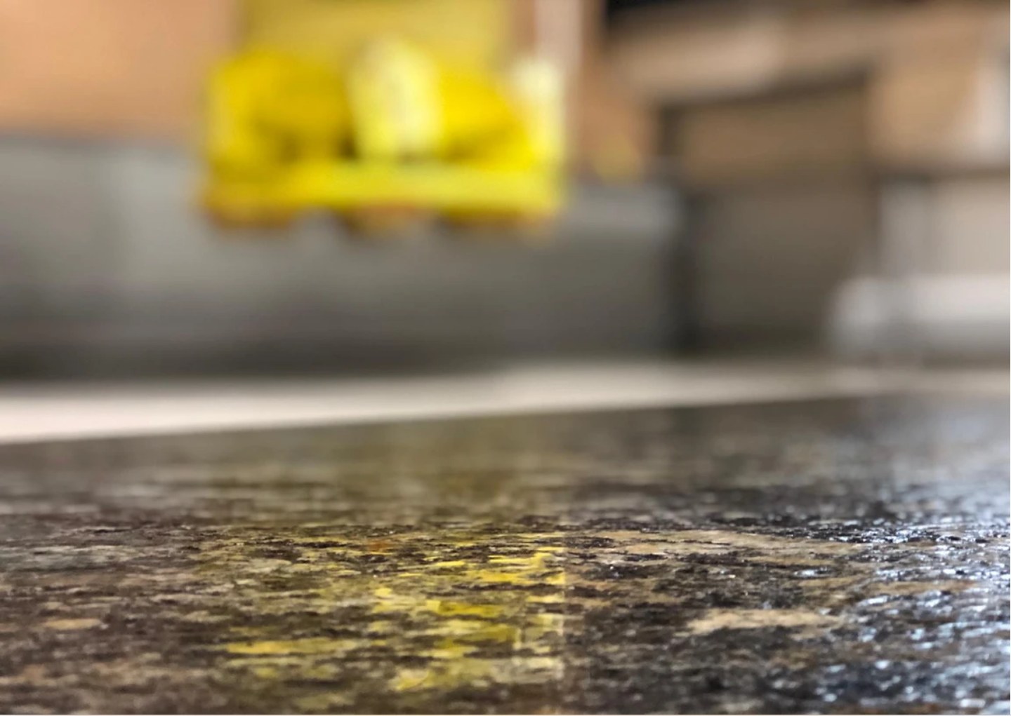 Close view along a finished granite countertop, shop lights reflected in its surface