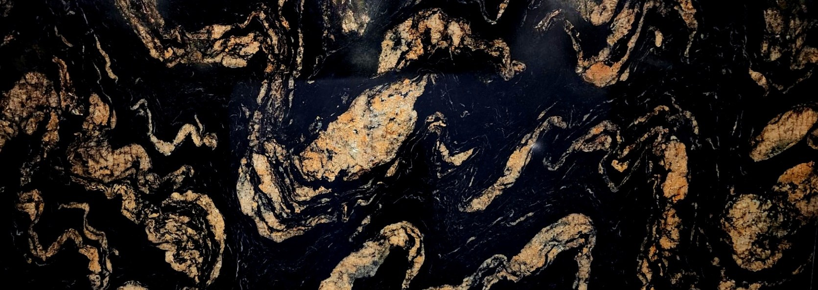 A polished black granite slab shot close, gold veining swirling across the face